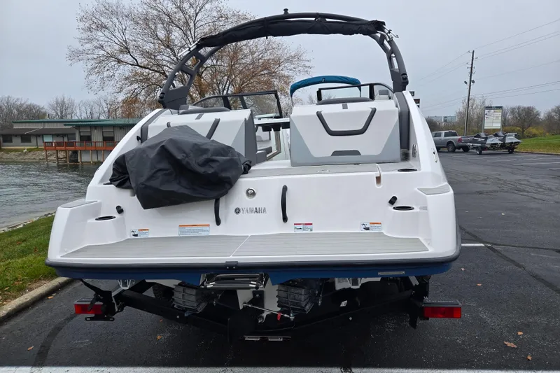 Slide: The Image of 2025 Yamaha Boats AR220, rear view, parked near water, showcasing sleek design and features. - 2