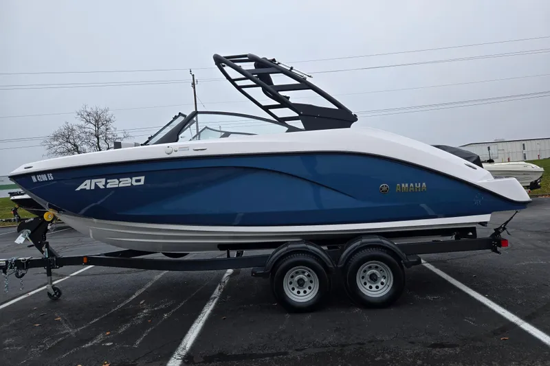 Slide: The Image of 2025 Yamaha Boats AR220 on trailer, blue and white design, parked in lot. - 4