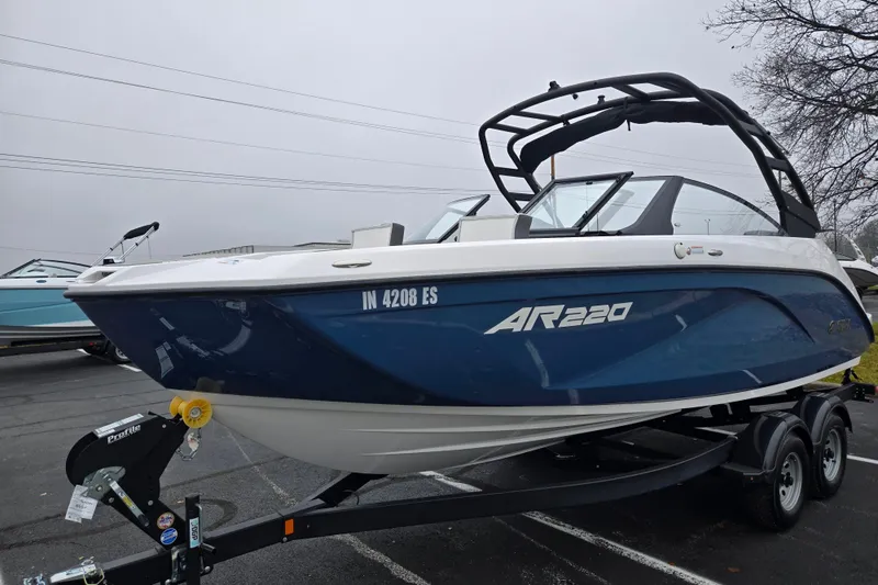 Slide: The Image of 2025 Yamaha Boats AR220 on trailer, sleek blue and white design, parked outdoors. - 5