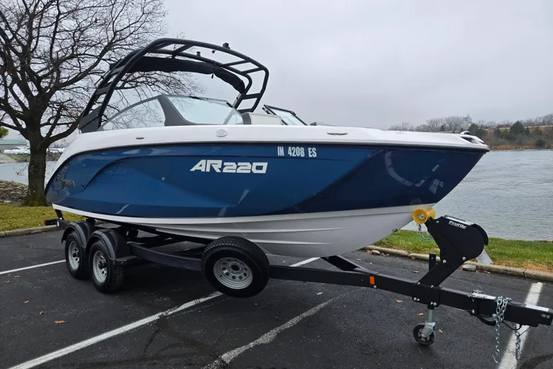 Slide: The Image of 2025 Yamaha Boats AR220 on trailer by a lakeside parking area. - 8