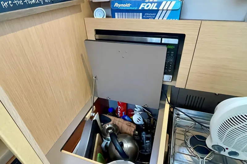 Slide: The Image of Compact kitchen area in a 2020 Beneteau Oceanis 38.1 sailboat with microwave and storage. - 19