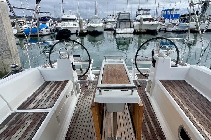 Slide: The Image of Beneteau Oceanis 38.1 sailboat cockpit with dual steering wheels, docked in a marina, 2020 model. - 2
