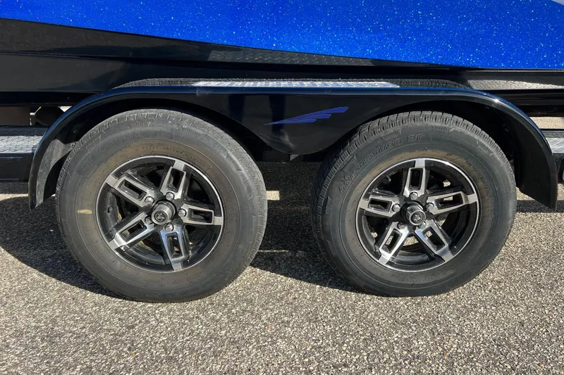 Slide: The Image of 2017 Tigé R21 trailer wheels with black rims on asphalt surface. - 11