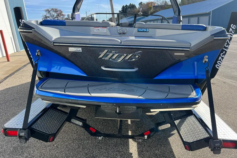 Slide: The Image of 2017 Tigé R21 boat rear view with blue and black design on trailer. - 14
