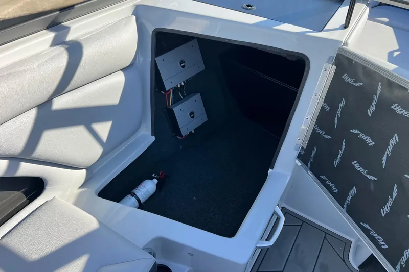 Slide: The Image of 2017 Tigé R21 boat interior storage compartment with fire extinguisher and electronic components. - 37