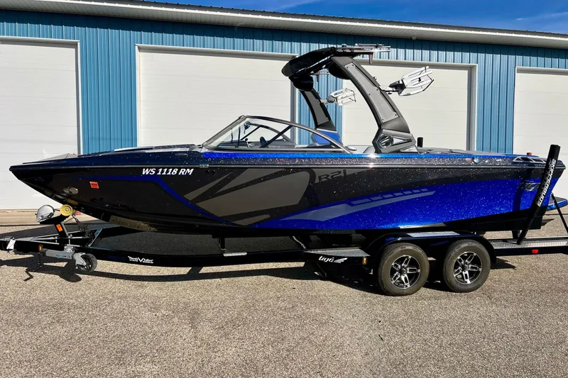 Slide: The Image of 2017 Tigé R21 boat with blue and black design on a trailer, parked outdoors. - 45