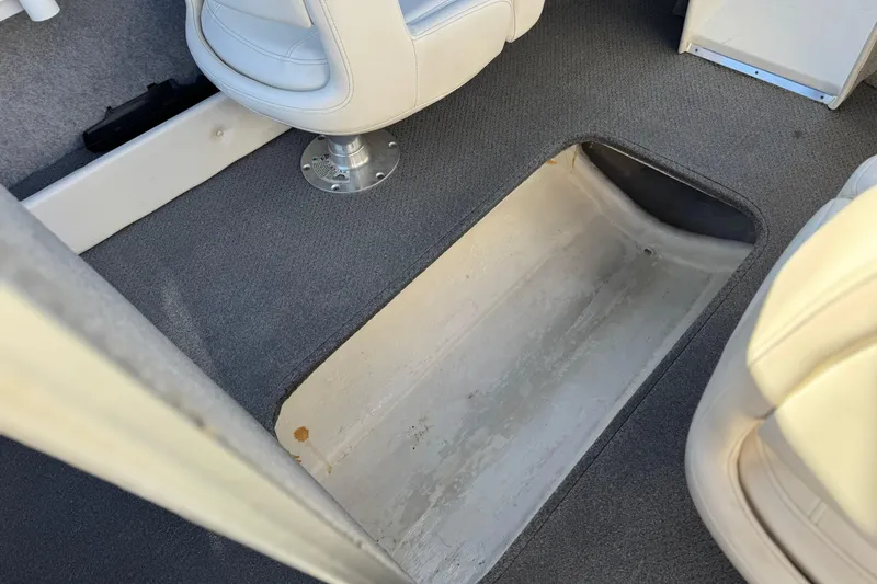 Slide: The Image of 2016 Bayliner 180 Bowrider interior storage compartment with gray carpet and white seating. - 16