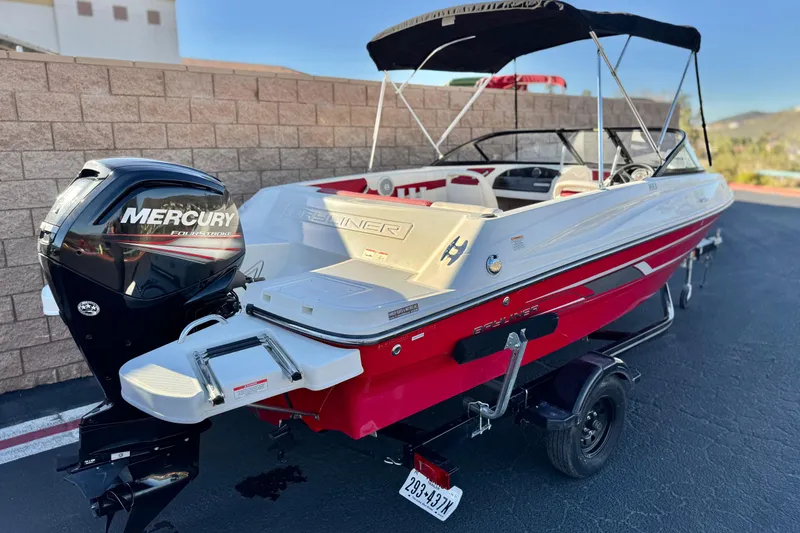 Slide: The Image of 2016 Bayliner 180 Bowrider with Mercury engine, red and white design, parked on a trailer. - 5