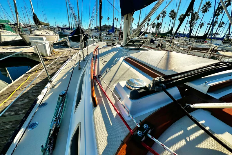 Slide: The Image of 1985 Catalina 36 sailboat docked at marina, surrounded by other boats and palm trees. - 12