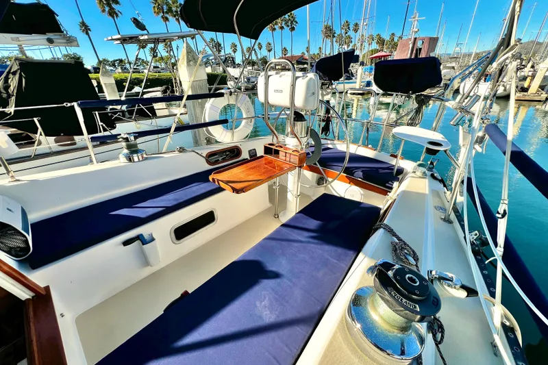 Slide: The Image of 1985 Catalina 36 sailboat cockpit with blue cushions, docked in a sunny marina. - 16