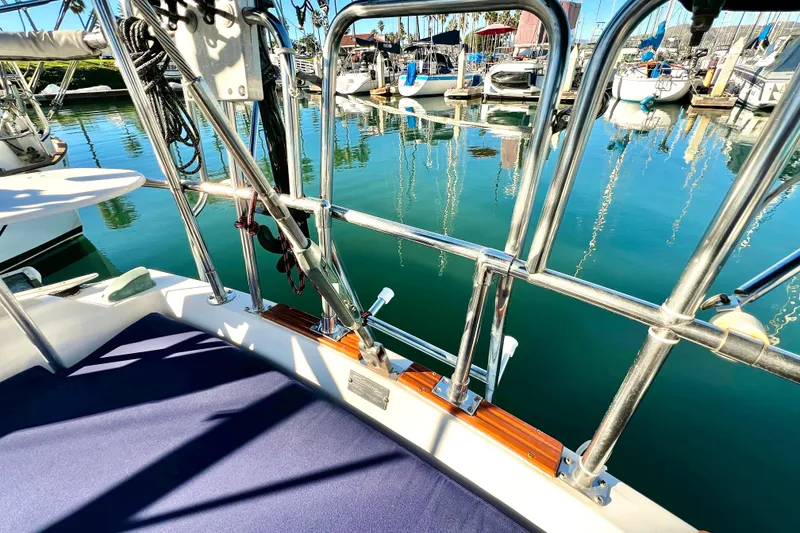 Slide: The Image of 1985 Catalina 36 sailboat deck with marina view, featuring polished railings and calm water reflections. - 18