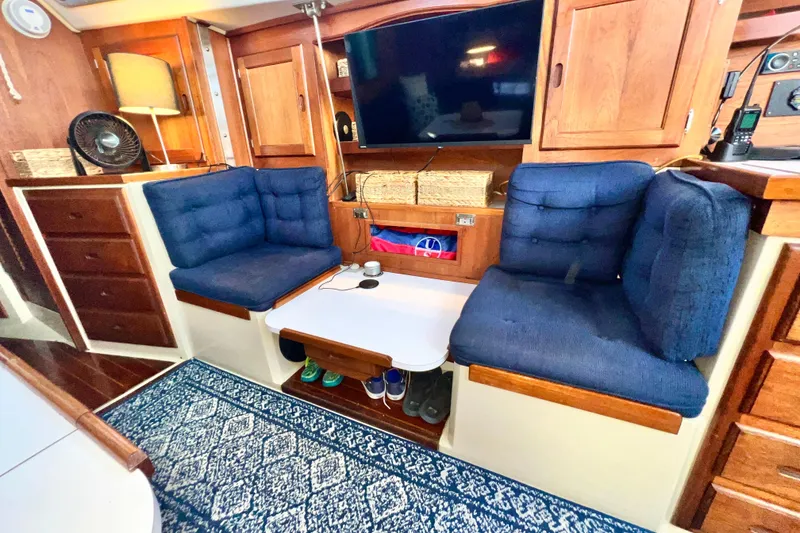 Slide: The Image of 1985 Catalina 36 yacht interior with blue cushions, wooden cabinets, and a TV. - 39
