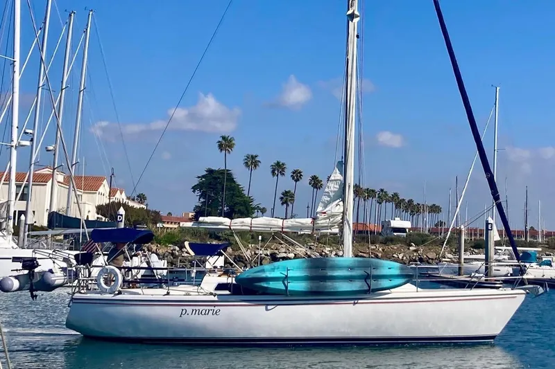 Slide: The Image of 1985 Catalina 36 sailboat docked in a marina with palm trees in the background. - 4