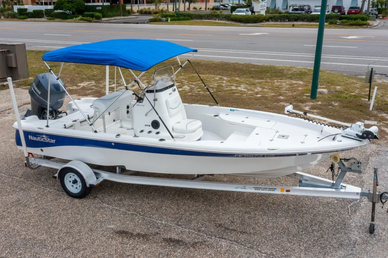 The Image of 2014 NauticStar 214 XTS boat with blue canopy on a trailer. - 0