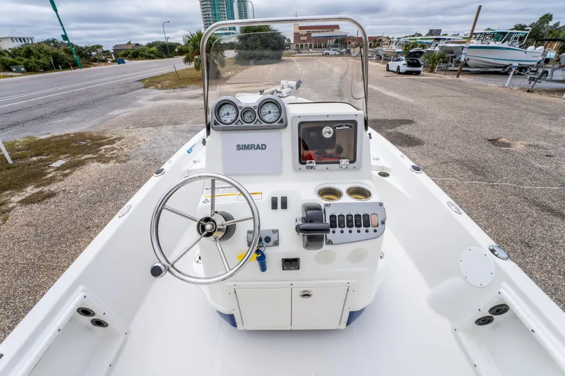 Slide: The Image of 2014 NauticStar 214 XTS boat dashboard with steering wheel and controls, parked near a road. - 13