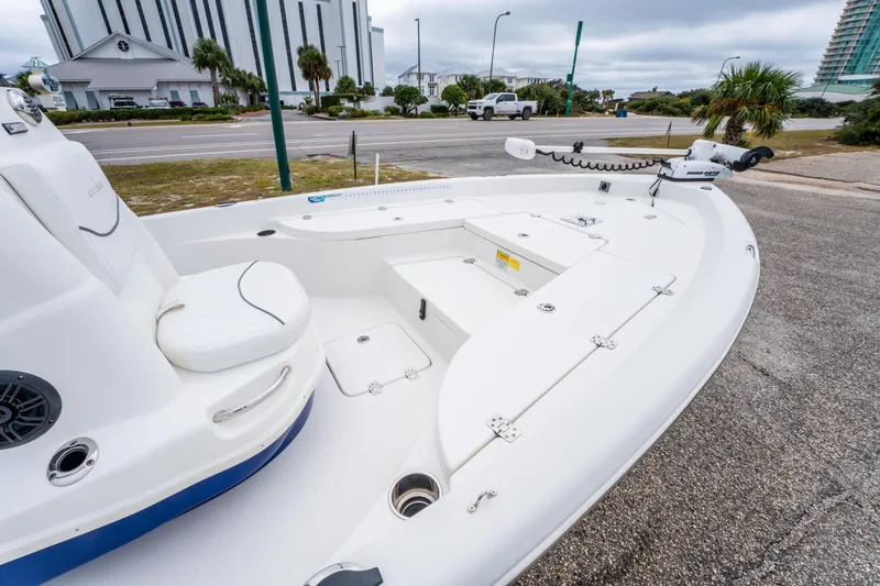 Slide: The Image of 2014 NauticStar 214 XTS boat with white seating and storage compartments, parked near a road. - 16