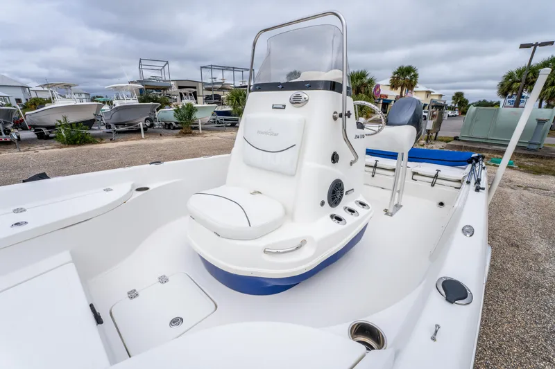 Slide: The Image of 2014 NauticStar 214 XTS boat interior with seating and console, parked outdoors. - 17