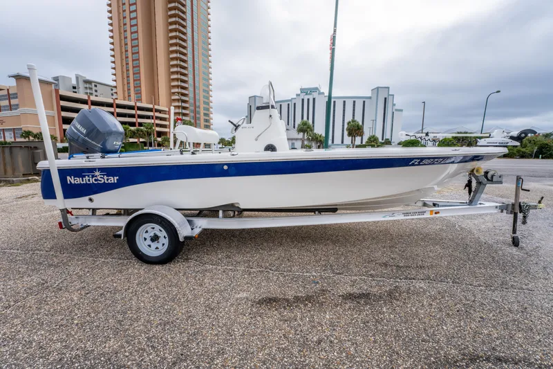 Slide: The Image of 2014 NauticStar 214 XTS boat on trailer, parked near tall buildings. - 3