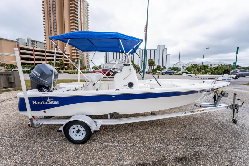 Slide: The Image of 2014 NauticStar 214 XTS boat with blue canopy on trailer, urban background. - 6