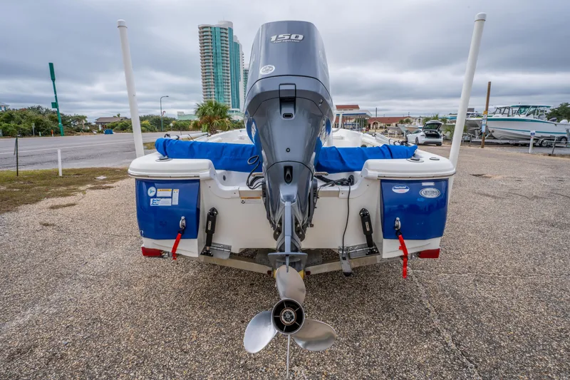 Slide: The Image of 2014 NauticStar 214 XTS boat with outboard motor, parked on gravel near tall buildings. - 9