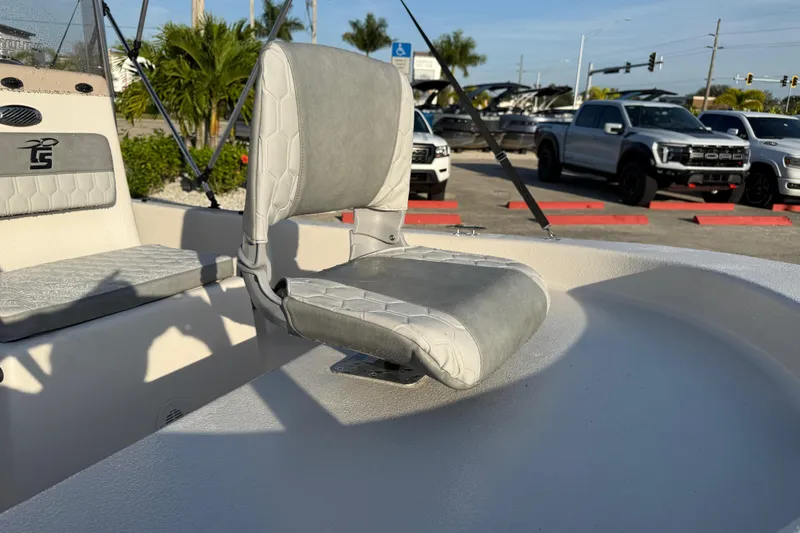 Slide: The Image of 2026 Carolina Skiff E16 JVX CC boat interior with gray seating, parked outdoors. - 18