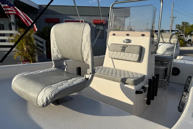 Slide: The Image of 2026 Carolina Skiff E16 JVX CC boat interior with seating and console, American flag in background. - 20