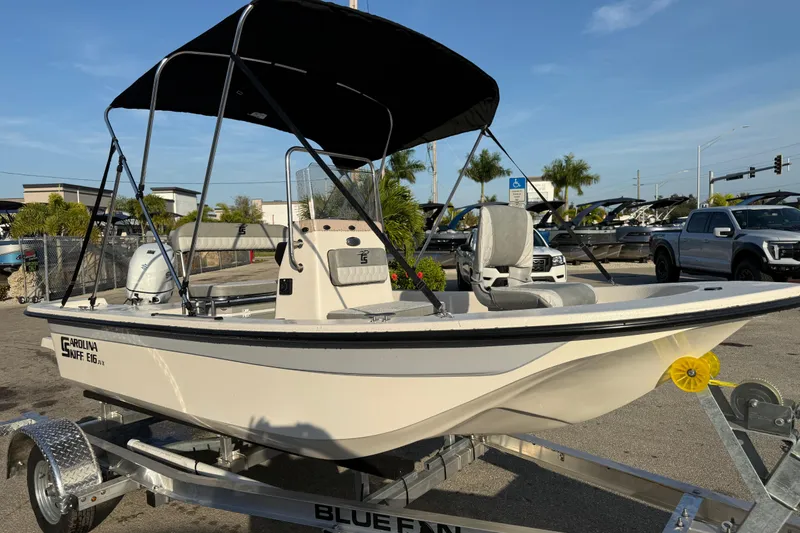 Slide: The Image of 2026 Carolina Skiff E16 JVX CC boat on trailer with canopy, parked outdoors. - 6