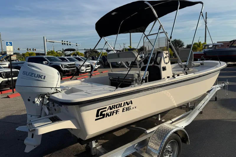 Slide: The Image of 2026 Carolina Skiff E16 JVX CC boat with Suzuki engine on trailer, parked outdoors. - 7