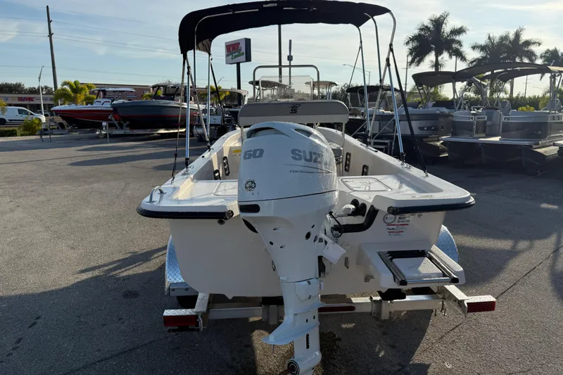 Slide: The Image of 2026 Carolina Skiff E16 JVX CC boat with Suzuki outboard motor in a sunny marina. - 9