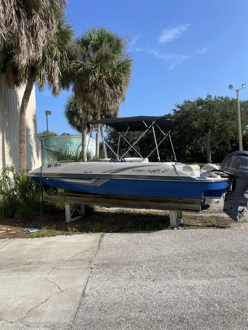 The Image of 2017 Starcraft MDX 211 O/B boat on trailer, parked near palm trees. - 0
