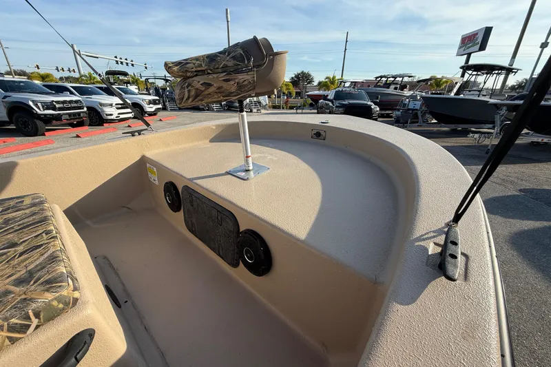 Slide: The Image of 2026 Carolina Skiff E18 JVX CC Sportsman Edition boat interior with camo seating, parked outdoors. - 13