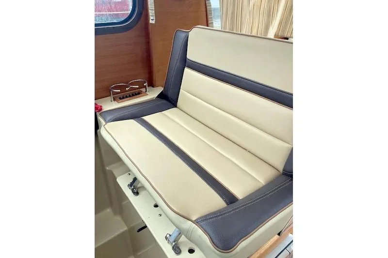 Slide: The Image of 2018 Ranger Tugs R-27 interior seat with beige and dark trim, wooden accents. - 14