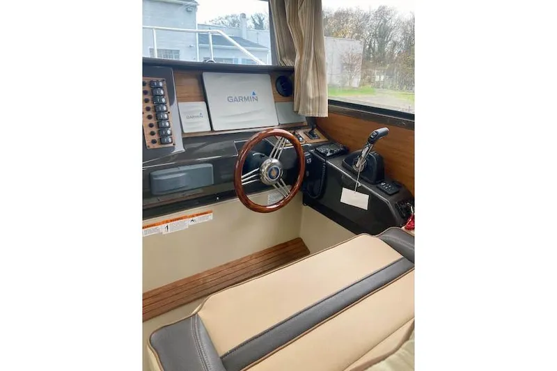 Slide: The Image of 2018 Ranger Tugs R-27 helm with Garmin navigation, wooden steering wheel, and control panel. - 15