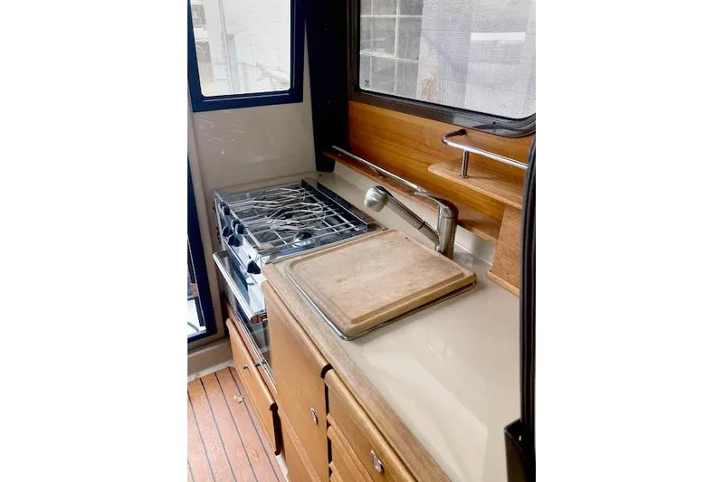 Slide: The Image of 2018 Ranger Tugs R-27 boat kitchen with stove, sink, and cutting board. - 17