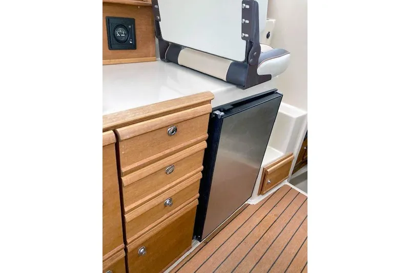 Slide: The Image of 2018 Ranger Tugs R-27 interior with wooden cabinetry and compact refrigerator. - 19