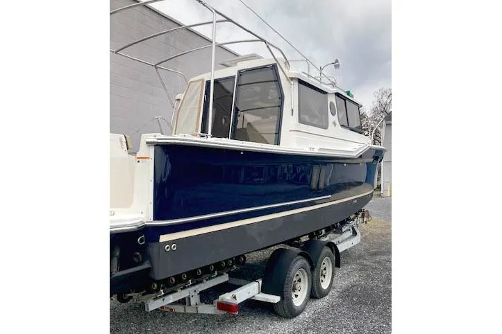Slide: The Image of 2018 Ranger Tugs R-27 boat on trailer, blue hull, parked outdoors. - 8