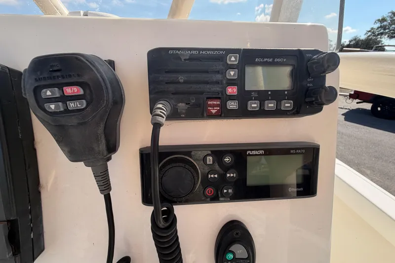 Slide: The Image of 2015 Pathfinder 2200 TRS boat interior with rod holders and console, parked outdoors. - 27