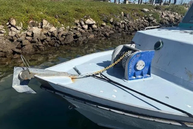 Slide: The Image of 1982 Willard Vega 30 boat with anchor and winch, docked near rocky shoreline. - 2