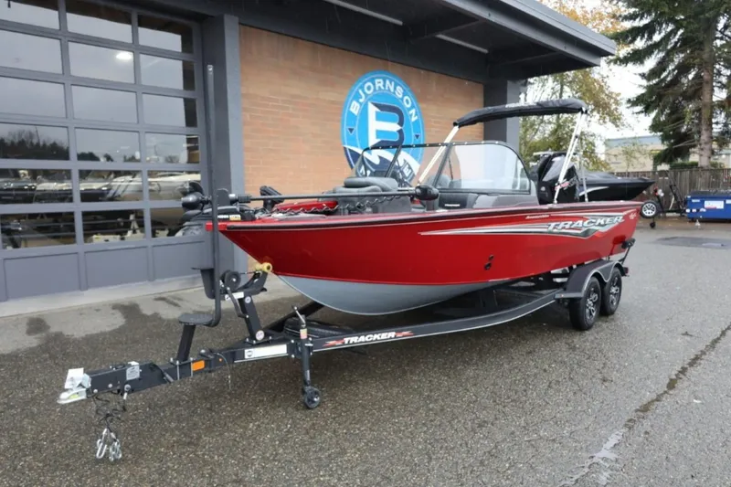 Slide: The Image of 2022 Tracker Targa V-19 Combo Tournament Edition boat in red, parked outside a showroom. - 13