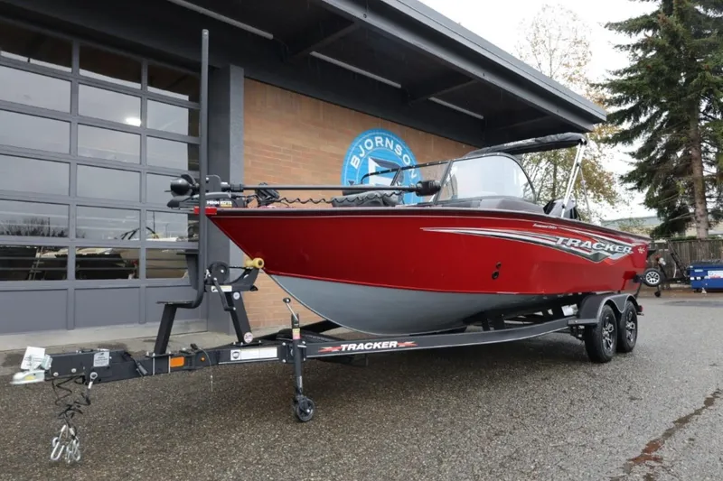 Slide: The Image of 2022 Tracker Targa V-19 Combo Tournament Edition boat on trailer, parked outside a garage. - 14