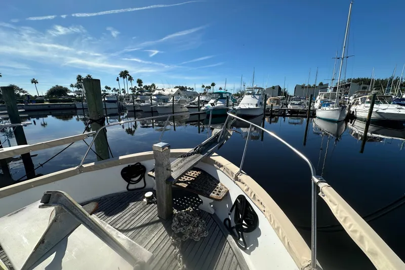 Slide: The Image of 1979 Marine Trader 38DC yacht docked in a serene marina under clear blue skies. - 11