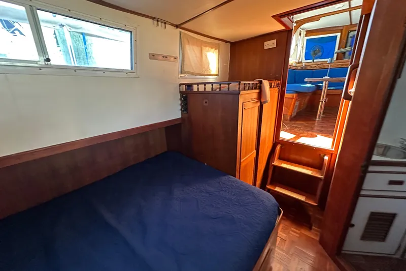 Slide: The Image of Interior cabin of 1979 Marine Trader 38DC with wooden furnishings and blue bedding. - 33