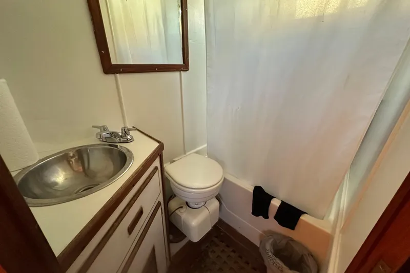 Slide: The Image of 1979 Marine Trader 38DC bathroom with sink, toilet, and shower curtain. - 35