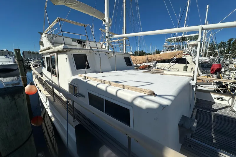 Slide: The Image of 1979 Marine Trader 38DC docked at marina, surrounded by other boats under clear blue sky. - 4