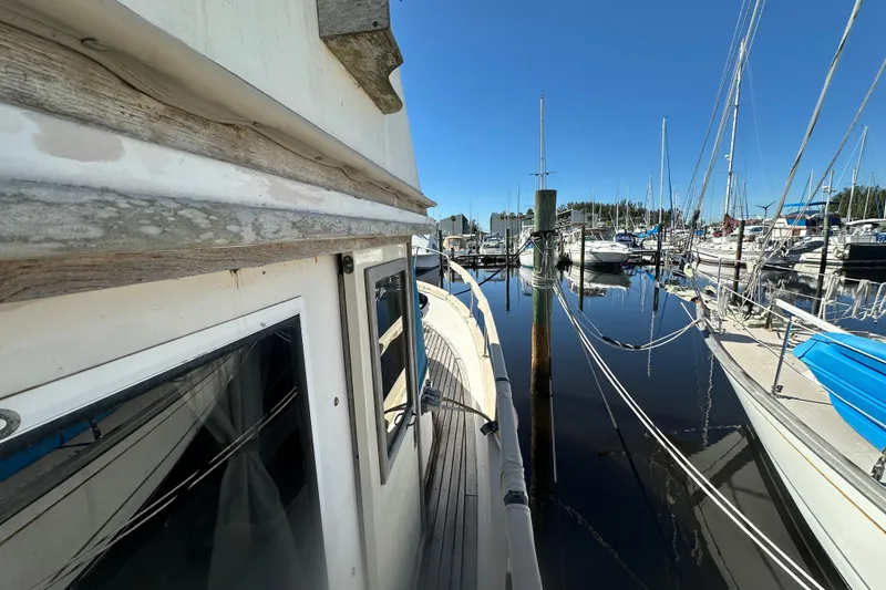 Slide: The Image of 1979 Marine Trader 38DC docked in a marina, surrounded by sailboats under a clear blue sky. - 9