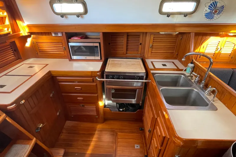 Slide: The Image of 1985 Passport 40 yacht kitchen with wooden cabinetry, dual sinks, and modern appliances. - 18
