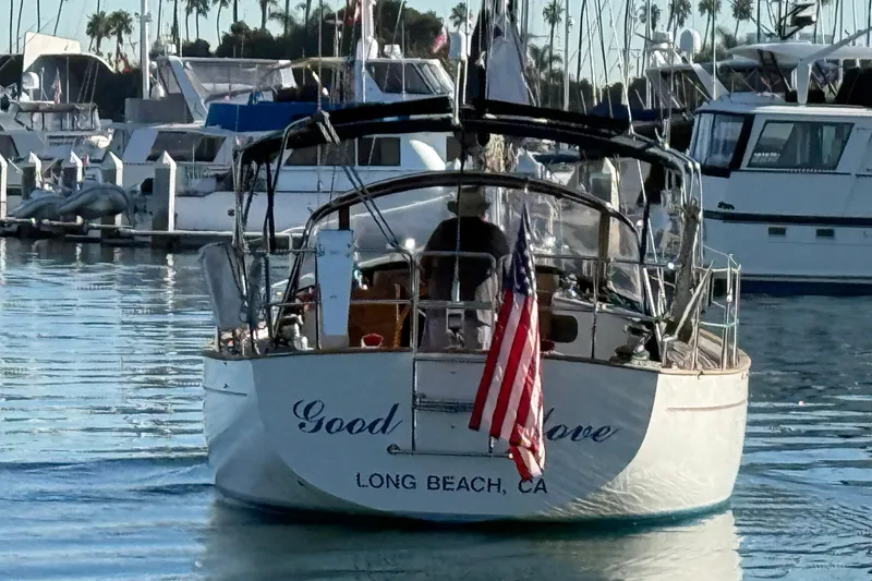 Slide: The Image of Sailboat "Good Love" docked in Long Beach marina, displaying American flag, Passport 40 model, 1985. - 2