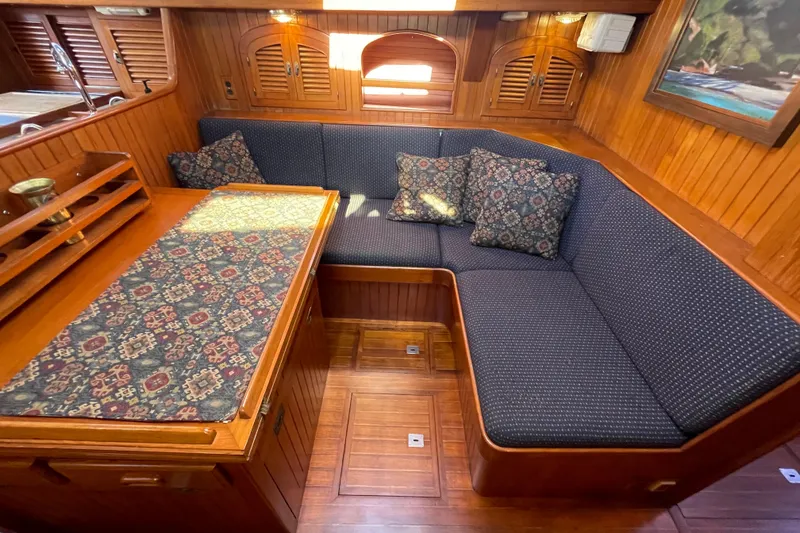 Slide: The Image of Cozy 1985 Passport 40 yacht interior with wooden paneling and cushioned seating area. - 22