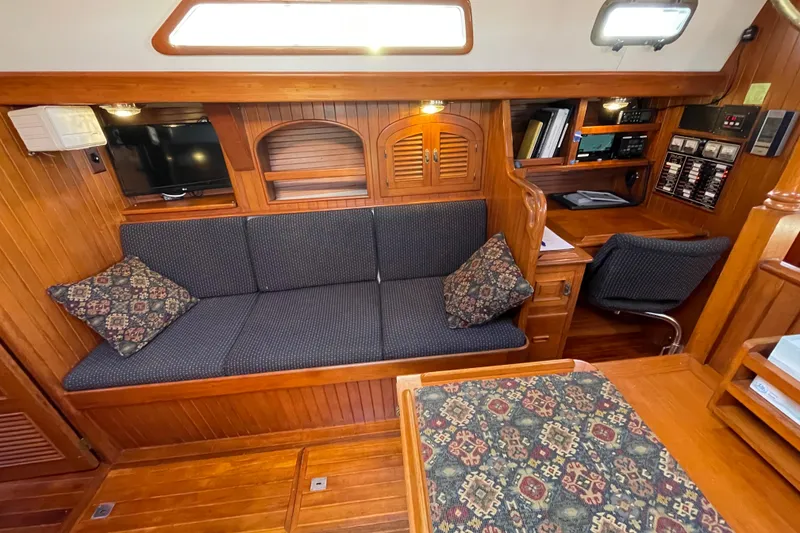 Slide: The Image of Cozy 1985 Passport 40 yacht interior with wooden finish, seating, and navigation desk. - 23
