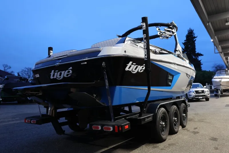 Slide: The Image of 2022 Tigé 24RZX boat on trailer, blue and black design, parked outdoors. - 51